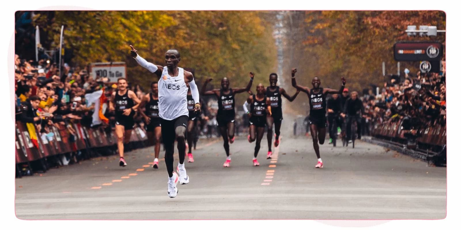 Marathon runners in a pack on a tree-lined road, still from a campaign video